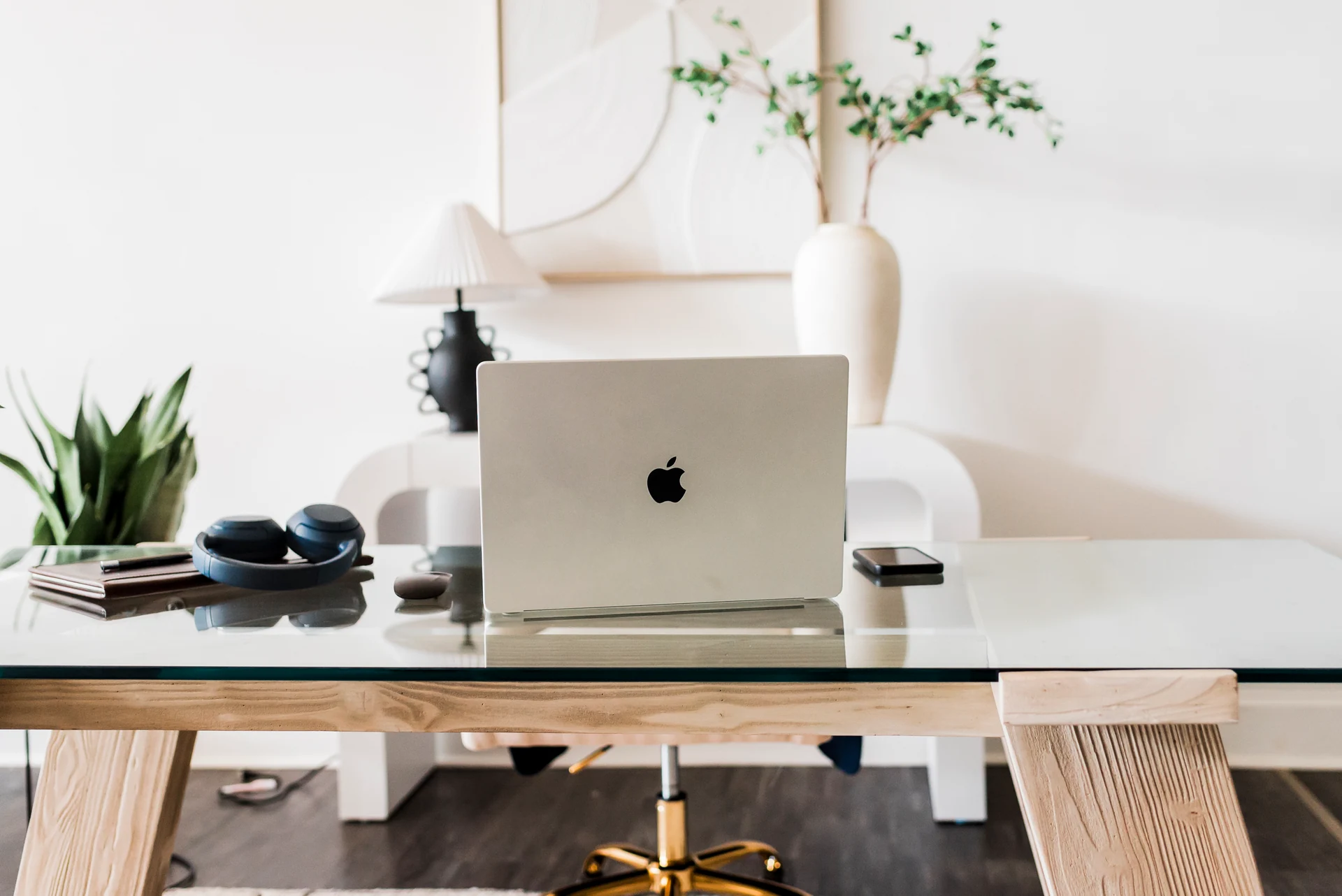 An empty desk with a laptop, notebook and headphones in Raymond’s office
