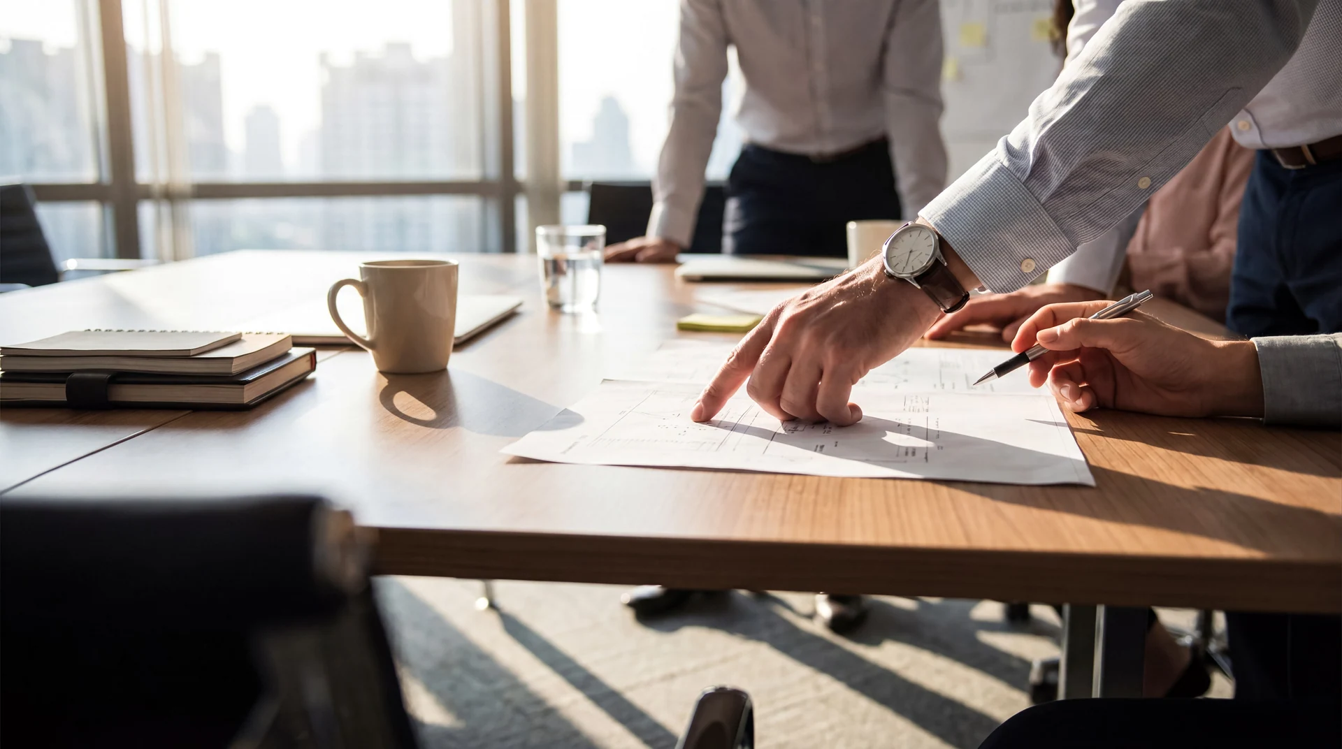 Colleagues reviewing a document together at a meeting table, with hands and notes in view